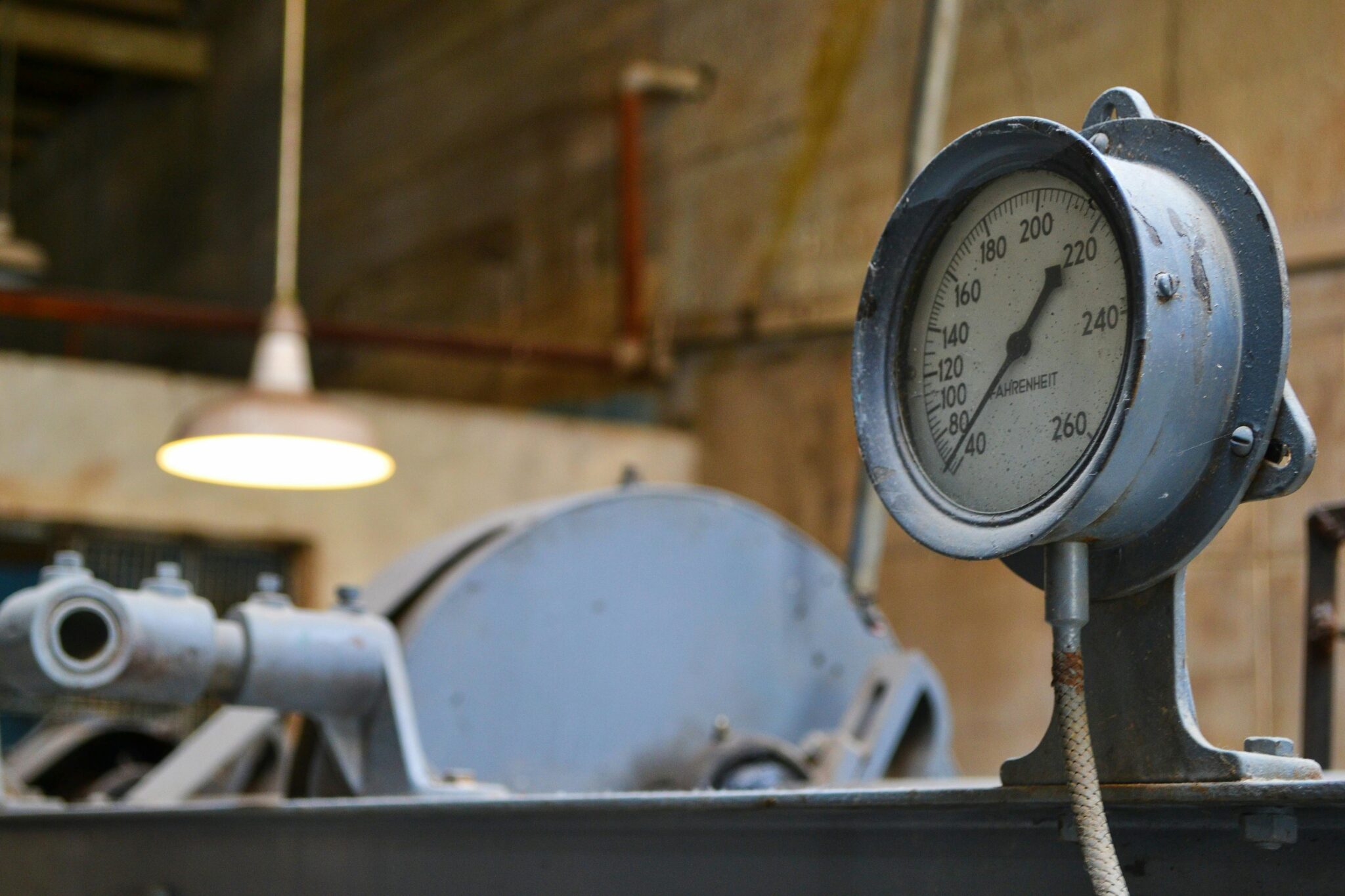 Detailed view of an old industrial pressure gauge in a workshop setting.